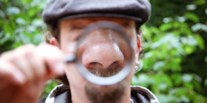 Persona con una lente d'ingrandimento che ingrandisce il naso.