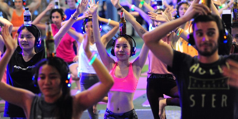 gruppo di persone che fanno yoga con una birra in testa 