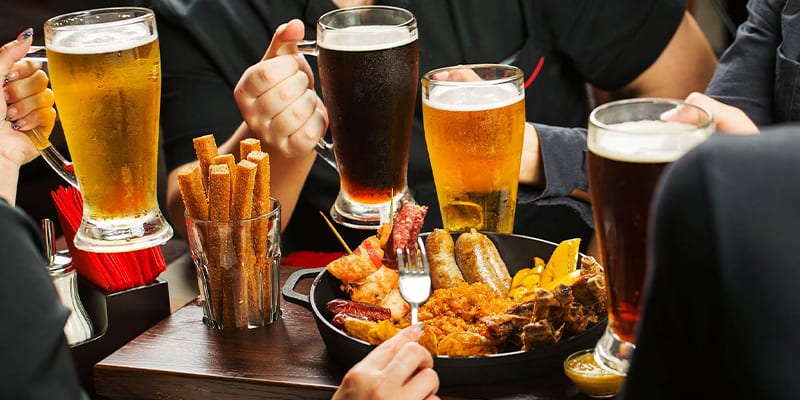 persone che mangiano carne alla griglia con birra